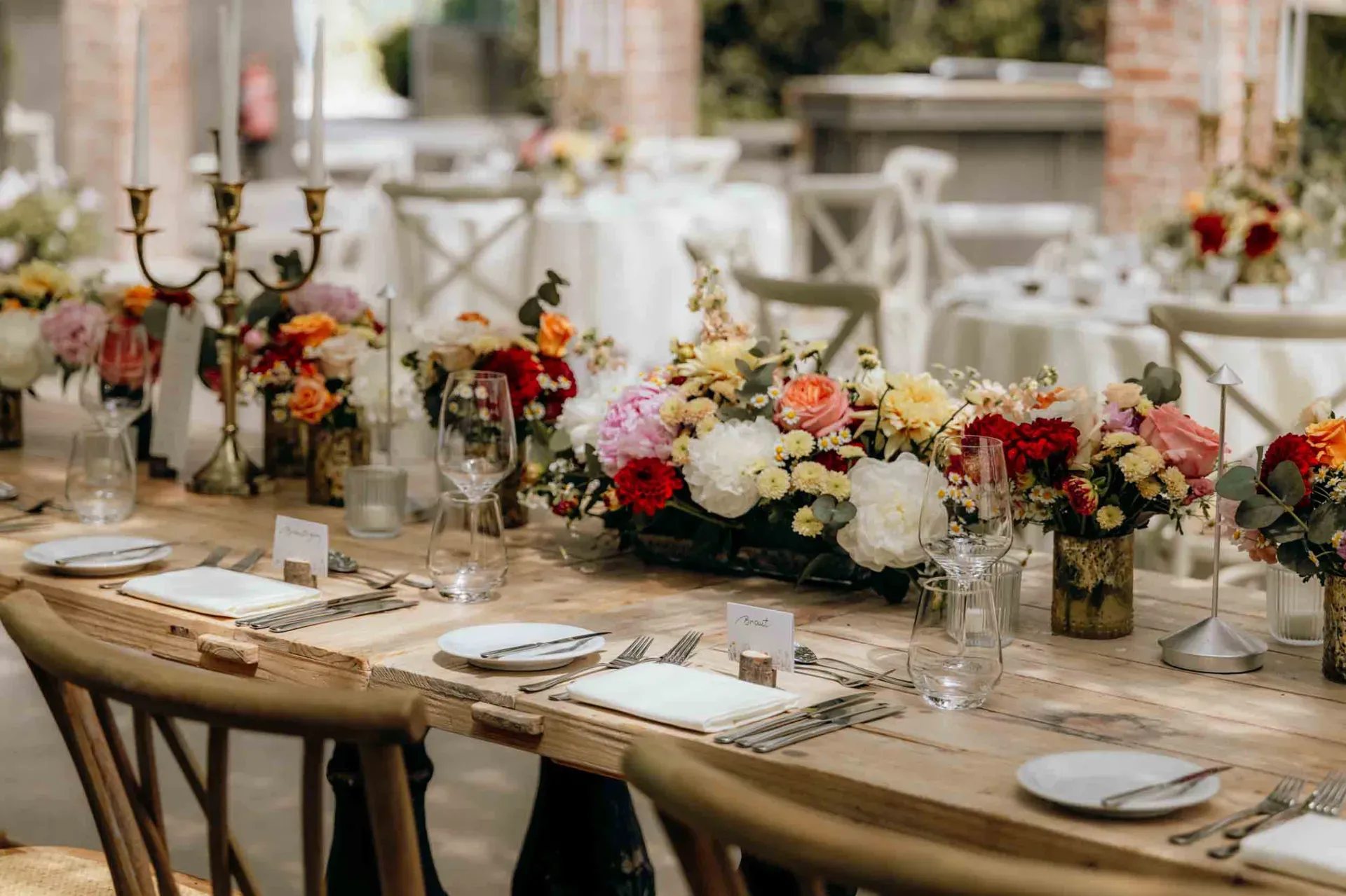 Eine festlich gedeckte Tafel mit Blumenarrangements bereitet den Rahmen für eine kleine Hochzeit in der Gärtnerei.