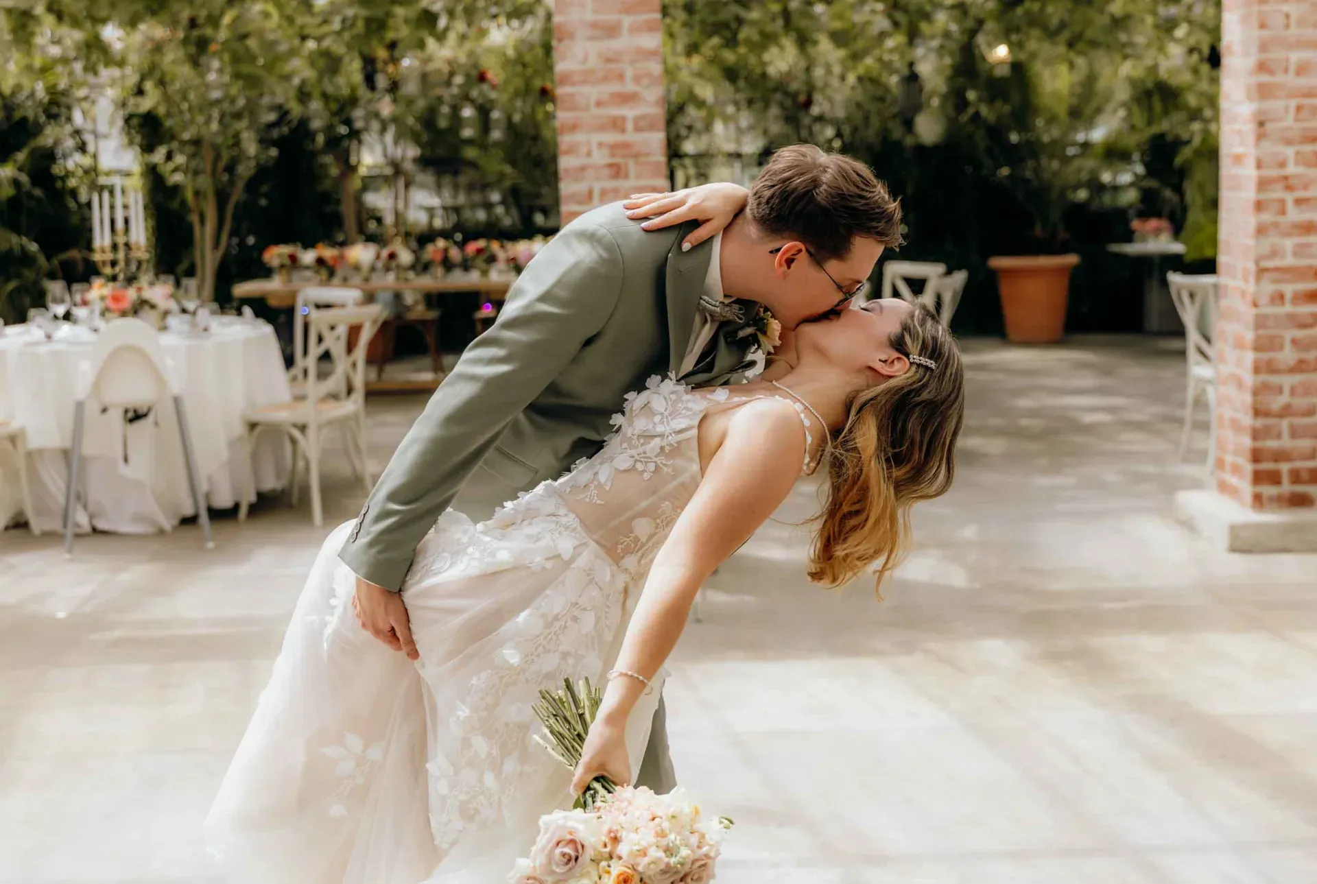 Ein Brautpaar zeigt sich innig bei einem Kuss während seiner kleinen Hochzeit in der Gärtnerei und genießt diesen Moment als Teil der Hochzeitsreportage.
