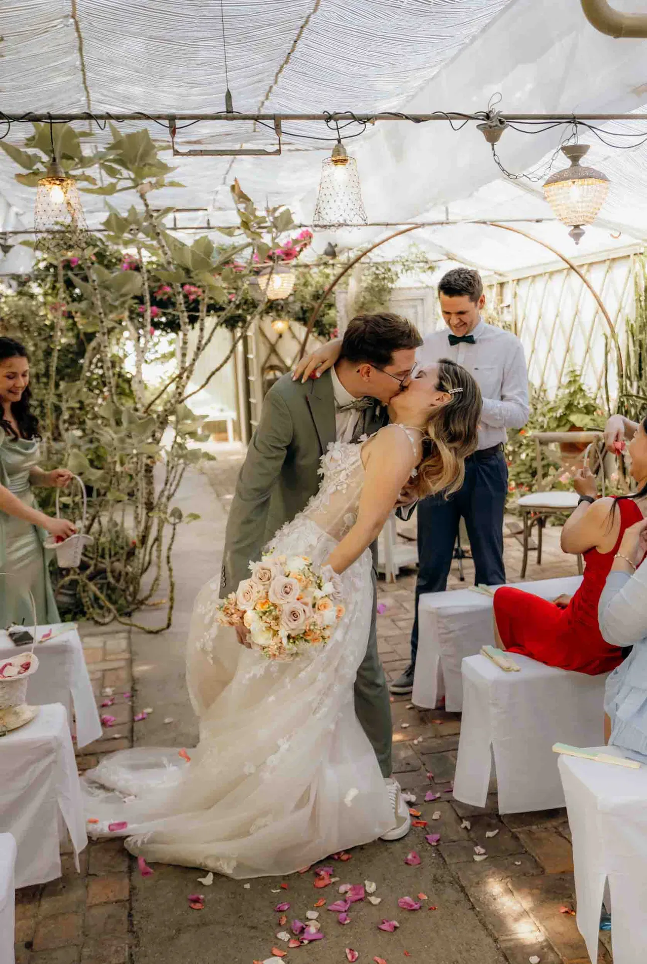Das Brautpaar küsst sich in der Gärtnerei inmitten der Gäste bei einer kleinen Hochzeit, festgehalten in einer authentischen Hochzeitsreportage.
