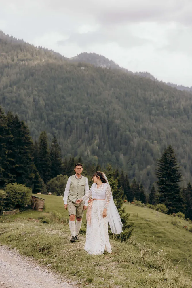 Brautpaar in Tracht Hand in Hand auf einem Bergpfad