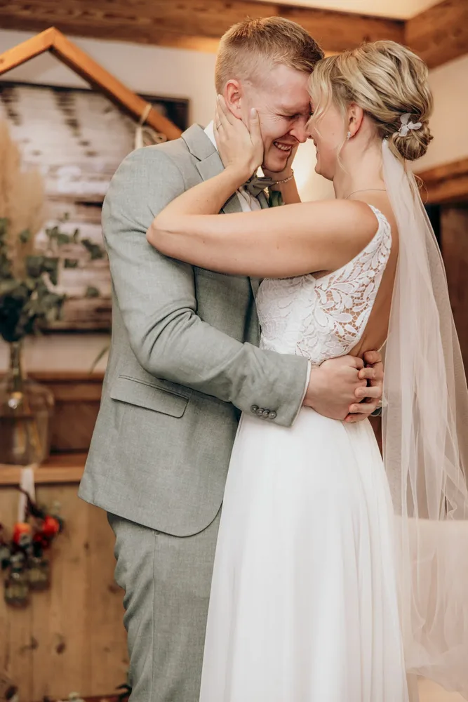 Brautpaar lächelt sich an, der Bräutigam im grauen Anzug. Hochzeitsfotograf MOKATI