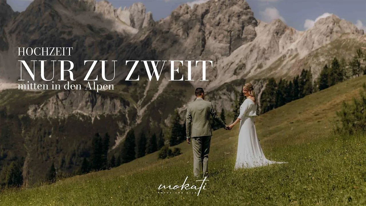 Brautpaar geht Hand in Hand über eine Almwiese, Titel „Hochzeit nur zu zweit mitten in den Alpen“, MOKATI Hochzeitsfilm