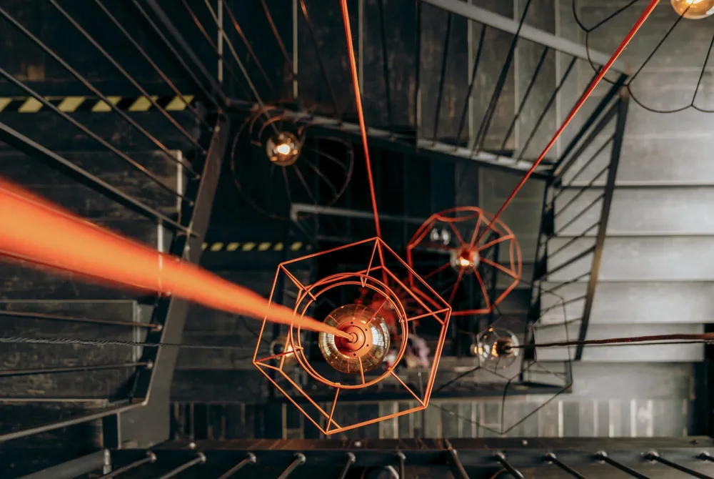 Rote Laserstrahlen durchschneiden einen dunklen Raum auf der Hochzeitsfeier. Hochzeitsfotograf MOKATI