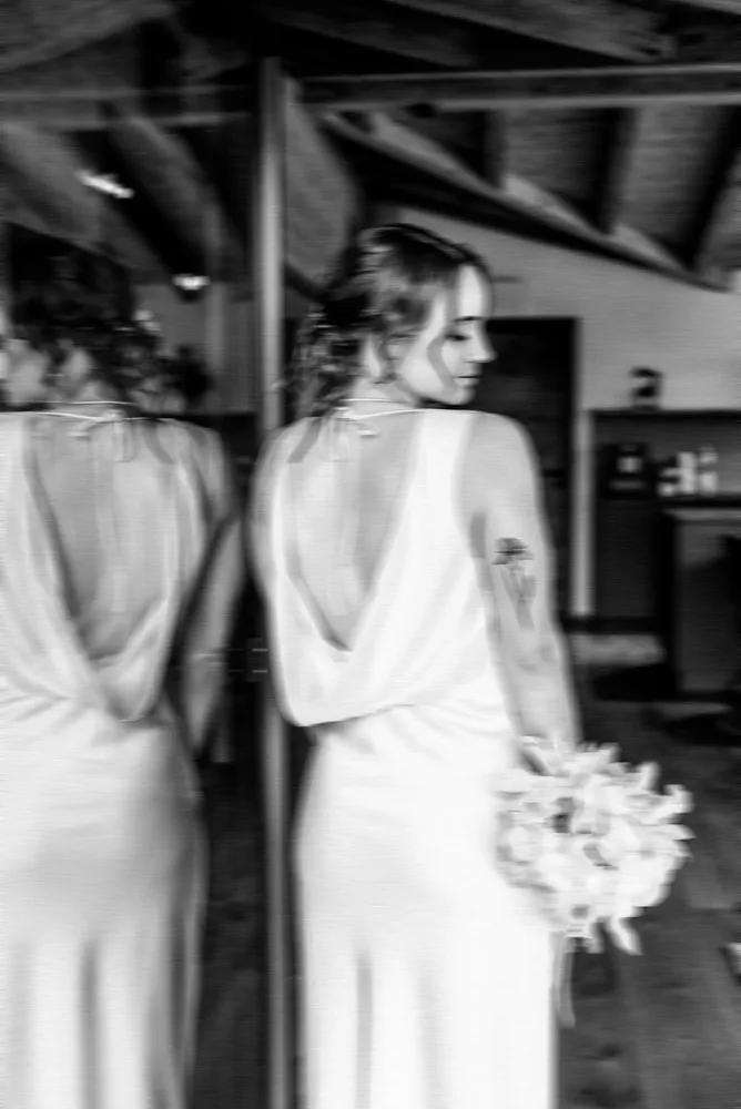 Schwarz-Weiß-Aufnahme einer Frau im Hochzeitskleid mit Blumenstrauß. Hochzeitsfotograf MOKATI