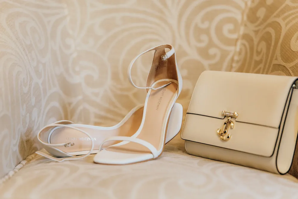Weiße Riemchensandalen mit Blockabsatz und eine cremefarbene Tasche. Hochzeitsfotograf MOKATI