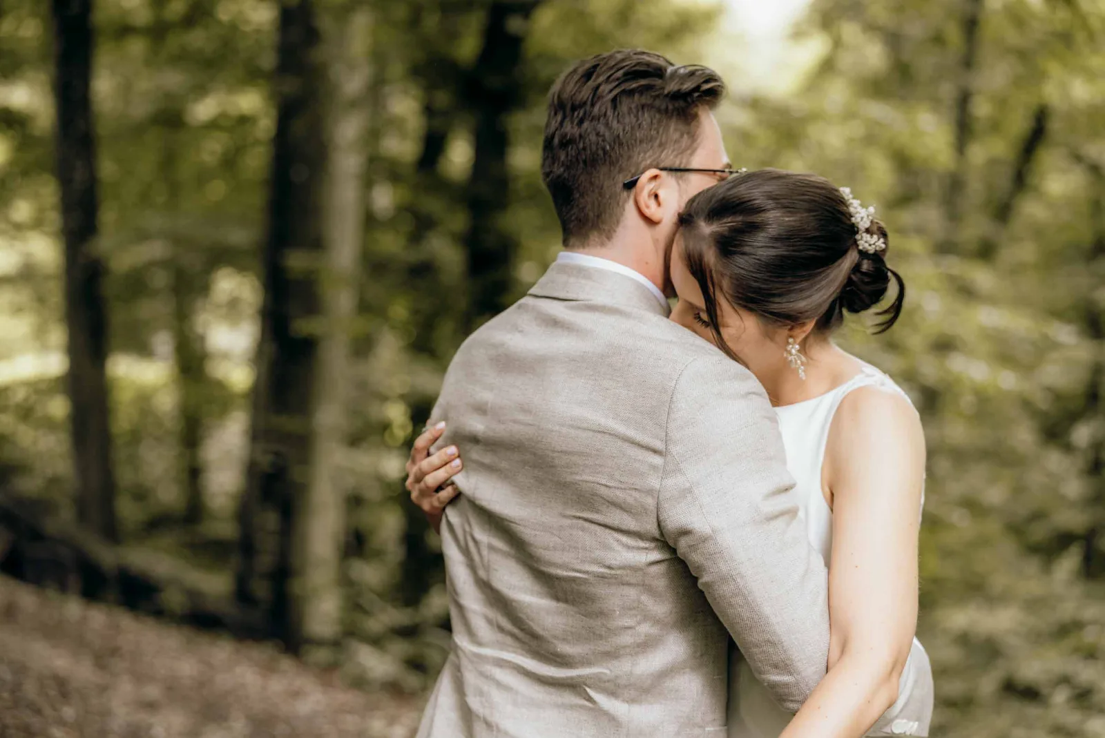 Ein Brautpaar umarmt sich innig im Wald, festgehalten von eurem Hochzeitsfotograf München auf den Weg zur Landgut Kugleralm.