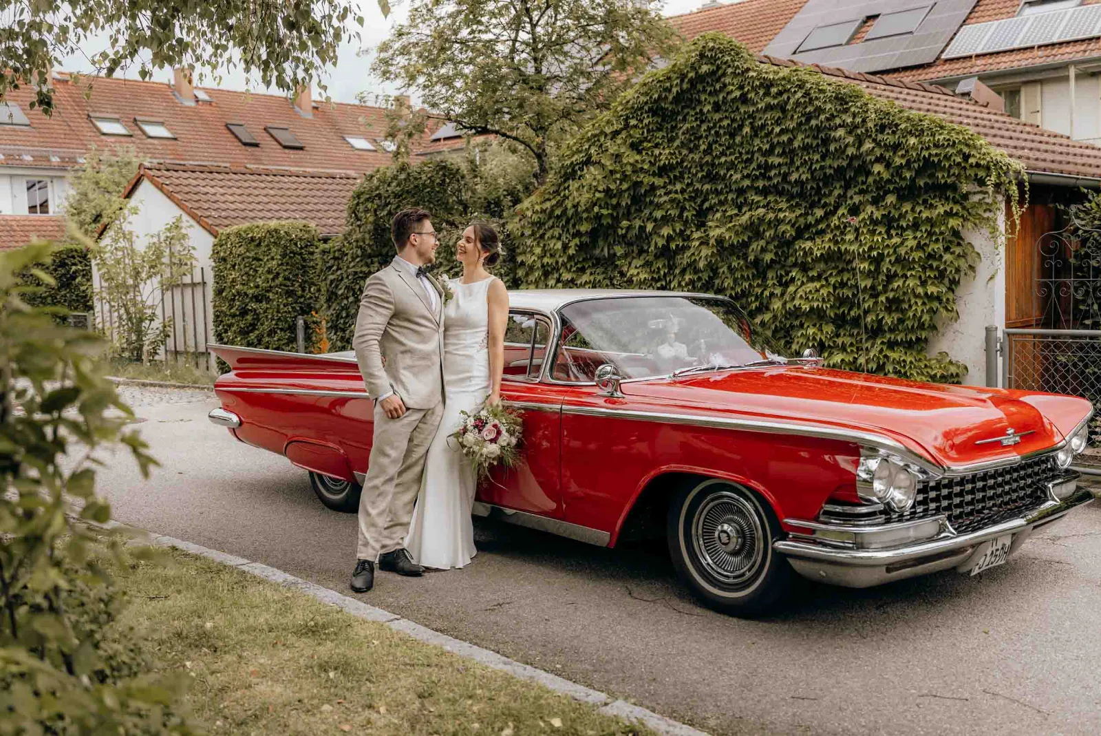 Ein Brautpaar lächelt sich neben ihrem Oldtimer an, festgehalten bei einer standesamtlichen Hochzeit von MOKATI als Foto und Film aus einer Hand.