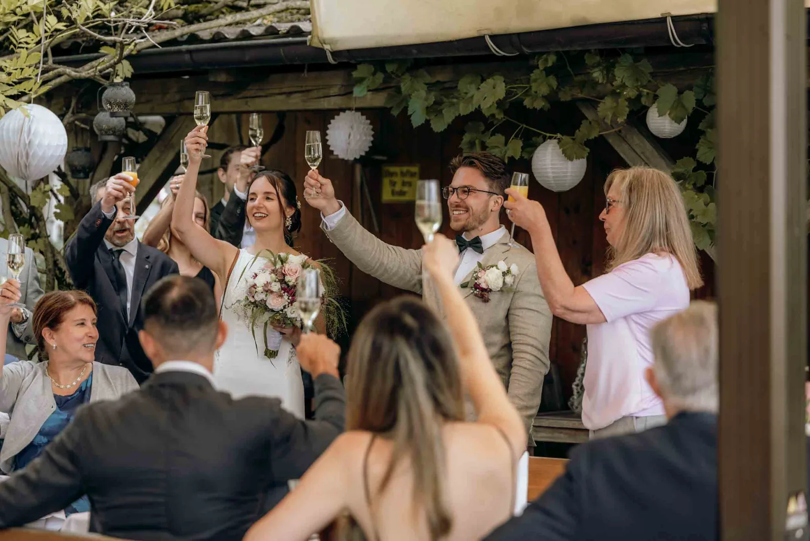 Das Brautpaar hebt in der Landgut Kugleralm als Hochzeitsfotograf München gemeinsam mit seinen Gästen die Sektgläser auf das neue Glück.