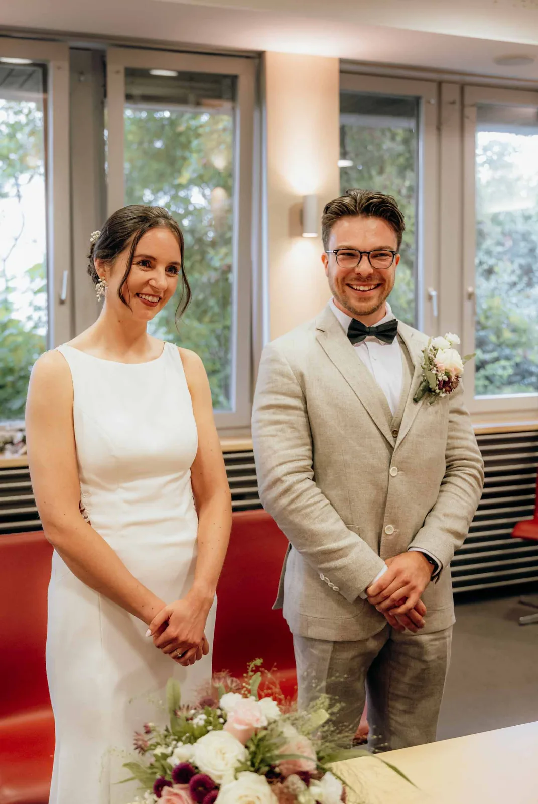 Brautpaar steht während der standesamtlichen Hochzeit in Poing erwartungsvoll und sichtlich glücklich nebeneinander.