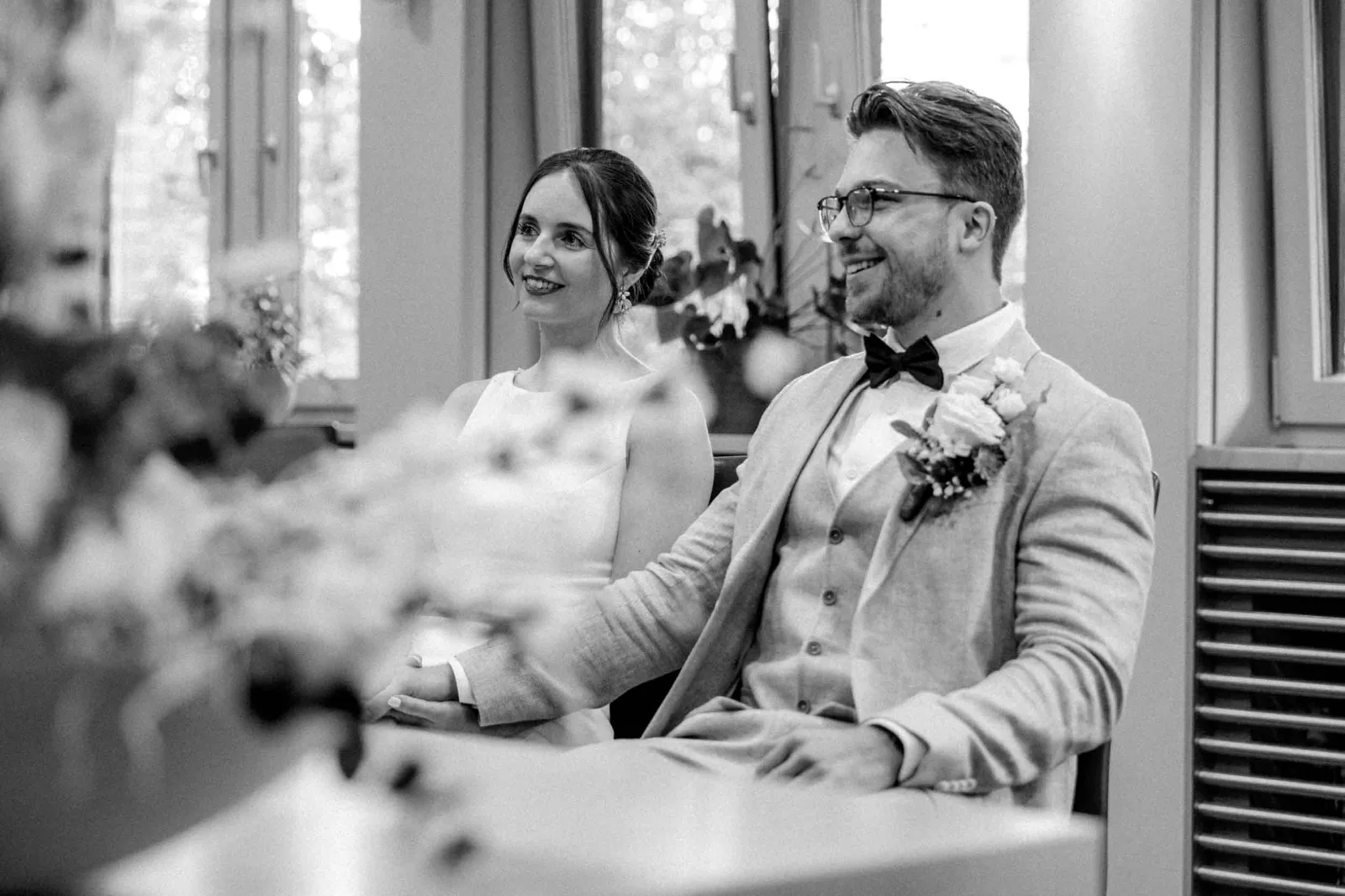 Das Brautpaar laechelt sich bei der standesamtlichen Hochzeit gluecklich zu, waehrend ich diesen Moment als Hochzeitsreportage festhalte.